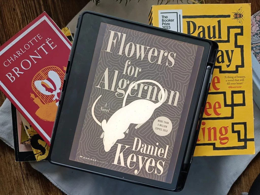 A  photo of Flowers for Algernon by Daniel Keyes open on Kindle Scribe, against a background of books for decor