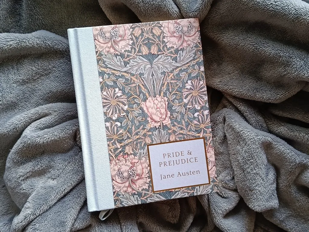 A photo of the book Pride and Prejudice by Jane Austen (the Wordsworth Heritage Collection Edition) against a soft gray blanket